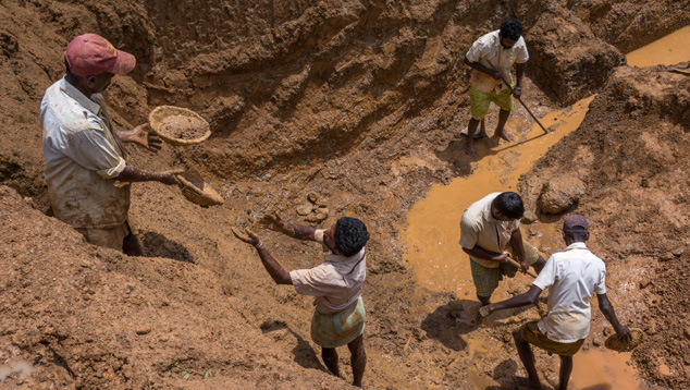 mall-scale gemstone mining in Sri Lanka, showing miners working in a shallow pit surrounded by earth, reflecting traditional methods used to extract rare gems.